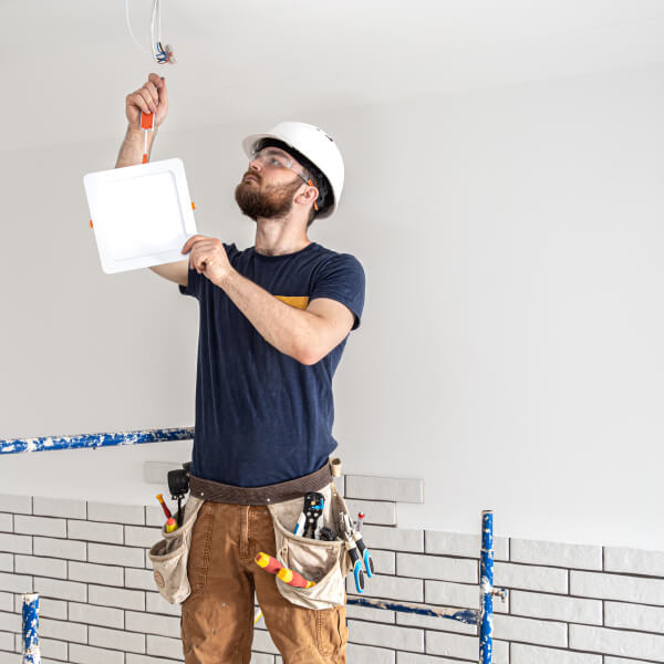 Un homme en sécurité manipulant un interrupteur dans une pièce pour installer un éclairage