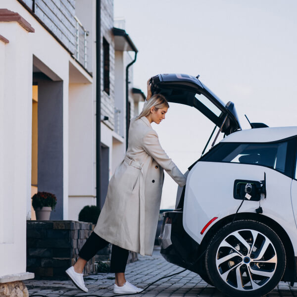 Une femme charge sa voiture dans un véhicule électrique, respectant le code et bénéficiant d'une installation professionnelle.
