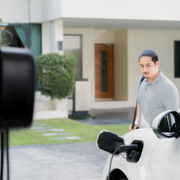 Un homme recharge sa voiture électrique, illustrant l'importance de la subvention et de l'emplacement pour une transition réussie.