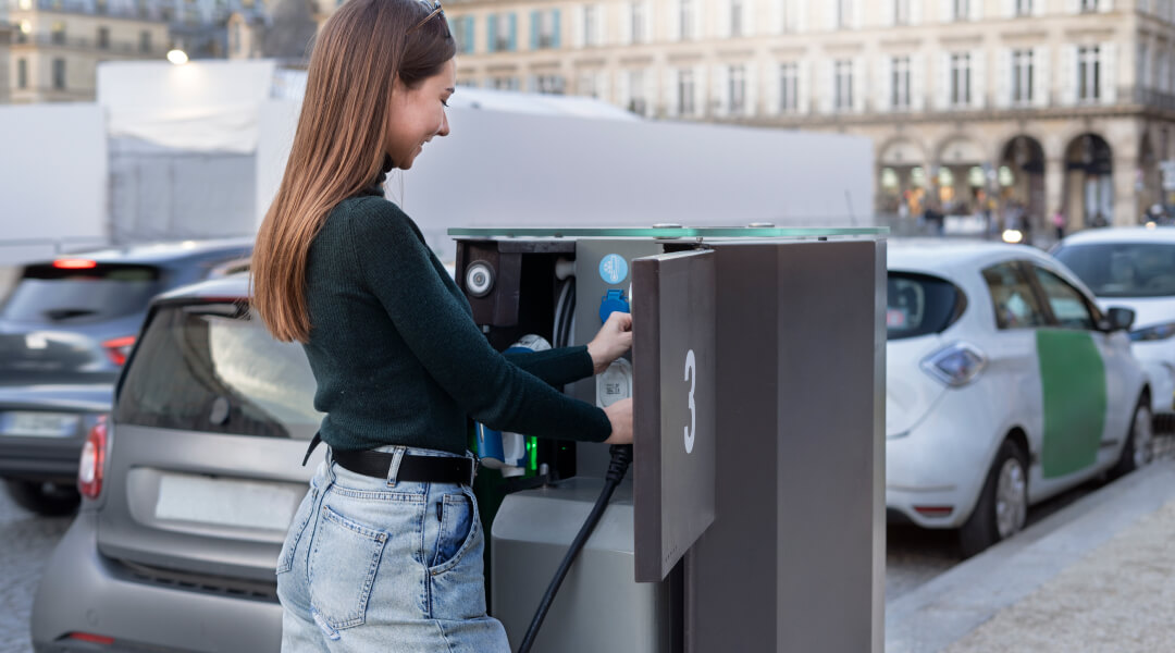 Une femme charge sa voiture à une station de recharge pour véhicules électriques au Québec, 2026.