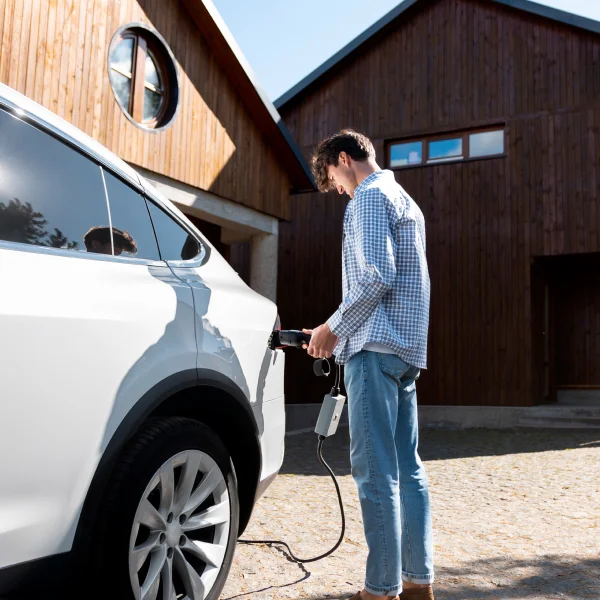 Un homme recharge sa voiture électrique à une station de recharge.