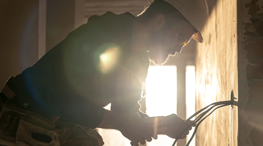 Un homme en casque de sécurité travaille sur un mur, utilisant une génératrice portative ou automatique.