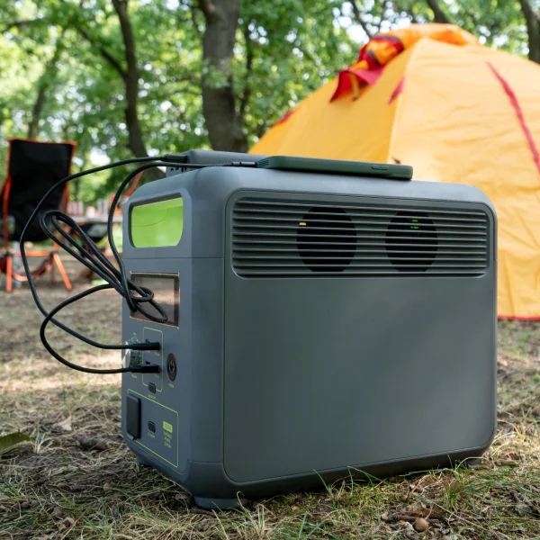 Génératrice portable posée sur l'herbe à côté d'une tente, prête à fournir de l'énergie pour le camping.