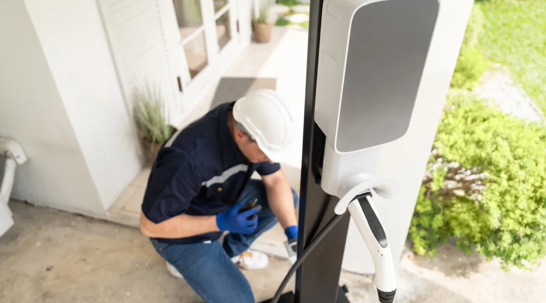 Un homme travaille sur un véhicule électrique, se concentrant sur le processus de recharge des véhicules électriques.